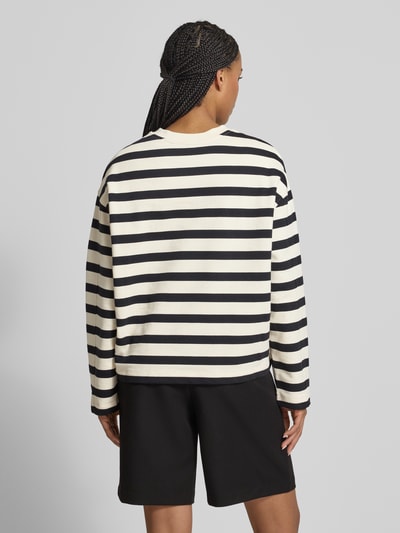Frauenmodel trägt Oversized Sweatshirt aus reiner Baumwolle Modell 'FRANKAA BOLD' von Armedangels, Two-Tone-Optik, gestreift, Label-Patch, Logo-Stitching, Rundhals, Langarm, Sweat, Rückenansicht Ganzkörperansicht.