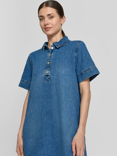 Vrouwenmodel draagt knielanges Jeanskleid mit Druckknopfleiste Modell 'Turo Alena' van MSCH Copenhagen, puur katoen, recht model, kentkraag, korte drukknoopsluiting, knielengte, ruglengte maat S 89 cm, borstwijdte maat S 44 cm, mouwlengte maat S 24 cm, blauwe denim, eenvoudige textuur, nahaufnahme bovenlichaam.
