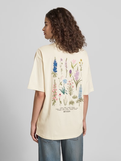 Frauenmodel trägt T-Shirt im Oversize-Fit mit Blumen-Backprint von REVIEW in Creme, reine Baumwolle, Rundhalsausschnitt, Halbarm, Label-Details, Rückenlänge bei Größe S: 67 cm, Ganzkörperansicht Rückansicht.