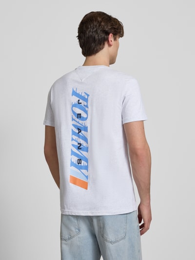 Männermodel trägt Regular Fit T-Shirt aus reiner Baumwolle von Tommy Jeans in Weiß mit blauem Label Print, Ganzkörperansicht Rückansicht.