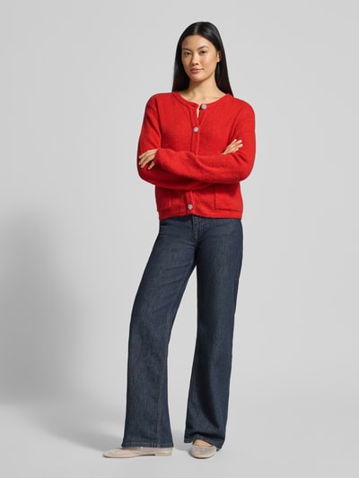 Frauenmodel trägt Strickjacke mit Knopfleiste Modell 'Hanni' von GUIDO MARIA KRETSCHMER WOMAN, leuchtend rot, lockerer Schnitt, Ganzkörperansicht von vorne.