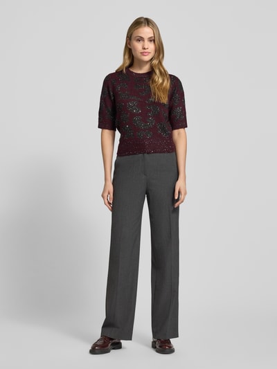 Vrouwenmodel draagt Shaped Fit Strickpullover met wol van Vero Moda, abstract motief, paars, pailletten, geribbelde boorden, vooraanzicht.