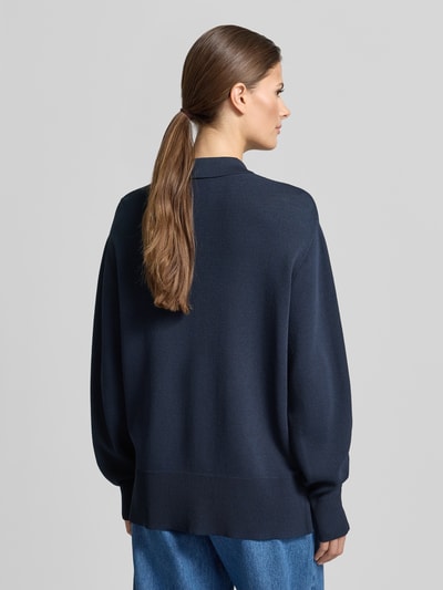 Frauenmodel trägt Strick-Polohemd im Wide Fit - curated by Tinvcb von SIC, dunkelblau, Strick-Optik, Relaxed Fit, Polo-Kragen, elastische Ärmelabschlüsse; Ganzkörperansicht Rückansicht.