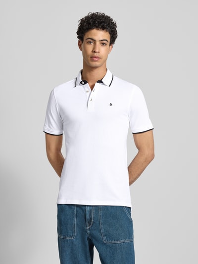 Männermodel trägt Slim Fit Poloshirt mit Viskose-Anteil Modell 'Paulos' von JACK & JONES, weiß mit schwarzen Details, Baumwoll-Mix, Logo-Stitching, Kurzärmelig, Polokragen, Rückenlänge bei Größe M 72 cm, Ganzkörperansicht von vorne.
