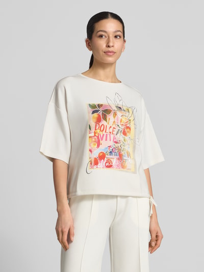 Vrouwenmodel draagt Relaxed Fit T-Shirt met Logo-Print van Christian Berg Woman, elastische materiaalmix met modal, logo-print, ronde hals, crèmekleur met kleurrijk voorpand, relaxed fit, vooraanzicht bovenlichaam.
