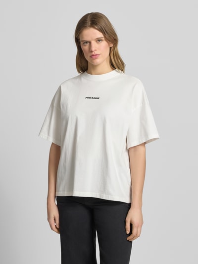 Modelka nosi damski t-shirt z bawełny, krój oversized fit, wyhaftowane logo, model 'BRACY' od Pegador, okrągły dekolt, długość tyłu w rozmiarze S: 61 cm, jasny kolor, gładka faktura, widok całej sylwetki z przodu.