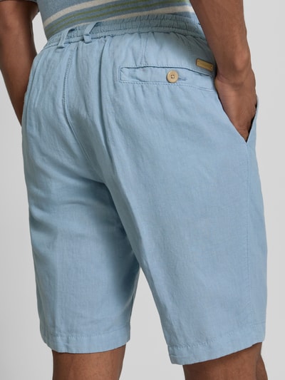 Männermodel trägt Regular Fit Bermudas mit Eingrifftaschen von bugatti aus hellem Leinen-Baumwoll-Mix, Gesäßleistentaschen, Ganzkörperansicht Rückansicht.