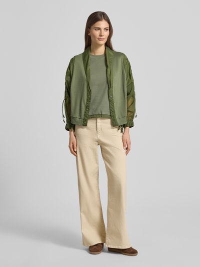 Kobiece model prezentuje Relaxed Fit Leichte Jacke im Material-Mix od Marc Cain, efekt: jednolity kolor, krój relaxed fit, krótki szalowy kołnierz, marszczenia, zapięcie na ukrytą listwę guzikową, rękaw o dł. 3/4, wykończenie materiału: satyna, szyfon, materiał: mieszanka bawełny; całopostaciowe ujęcie z przodu.