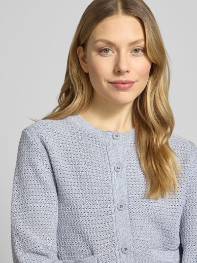 Modelka kobieca nosi kardigan rozpinany z bawełny, krój regular fit, model 'Biaphy' od Drykorn, nakładane kieszenie, okrągły dekolt, listwa guzikowa, elastyczne wykończenia, długość tyłu w rozmiarze S: 50 cm, długość rękawów w rozmiarze S: 65 cm, jasnoniebieska faktura dzianiny, zbliżenie na górną część ciała