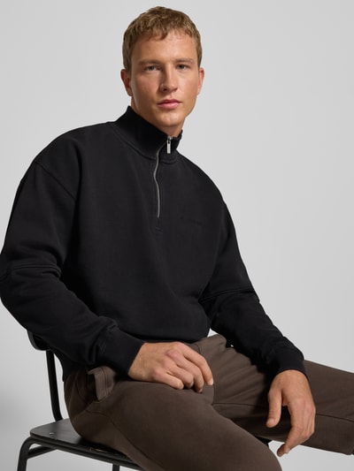 Męskimodel nosi Oversized Sweatshirt mit Stehkragen von Pegador, mieszanka bawełny, krój oversized, stójka, prążkowane wykończenia, krótki zamek błyskawiczny, wyhaftowane logo, długość tyłu 67 cm, długość rękawa 61 cm, widok z przodu, ujęcie zbliżeniowe na górną część ciała.