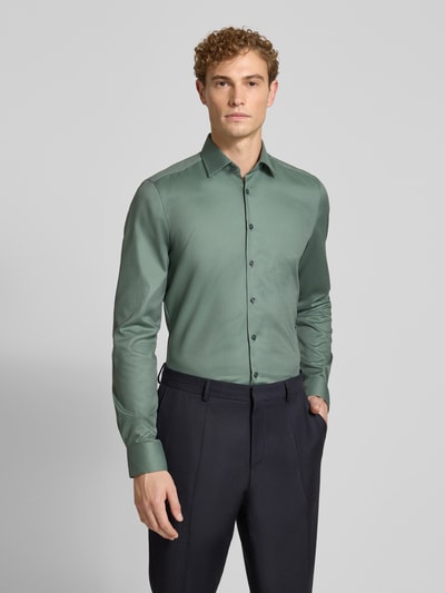 Männermodel trägt Body Fit Businesshemd mit extra langem Arm von OLYMP in Grün, glatte Textur, Ganzkörperansicht von vorne. Herren Businesshemd von OLYMP Level 5