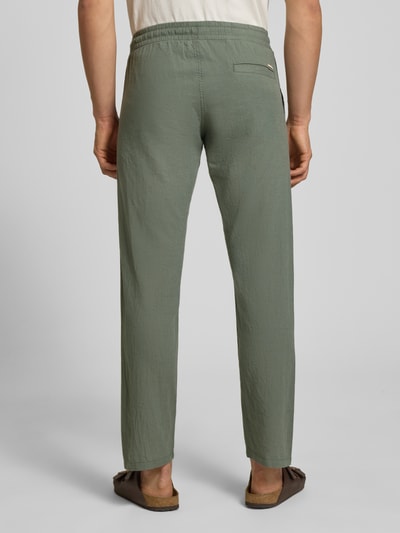 Męski model nosi Hose aus Baumwoll-Leinen-Mix Modell 'KANE' von Jack & Jones, zielony kolor, krój regular fit, elastyczny pas, Szerokość w rozmiarze M: 41 cm, długość nogawki wewnętrznej w rozmiarze M: 81 cm, zdjęcie całej sylwetki z tyłu.