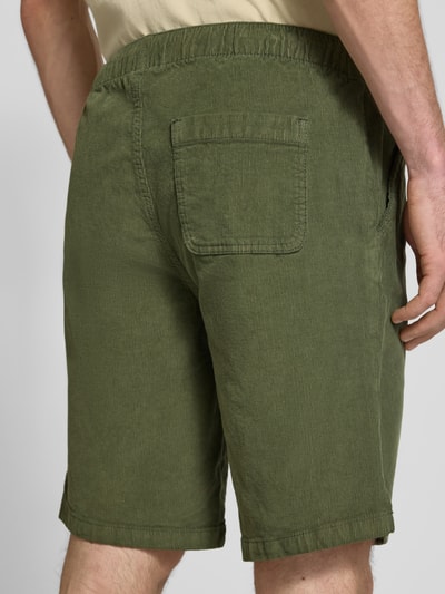 Männermodel trägt Regular Fit Shorts mit Tunnelzug Modell 'Joey' von Redefined Rebel aus grünem Cord, Baumwoll-Elasthan-Mix, Ganzkörperansicht Rückansicht. Herren Shorts, Bundweite bei Größe M: 39 cm, Innenbeinlänge bei Größe M: 25 cm.