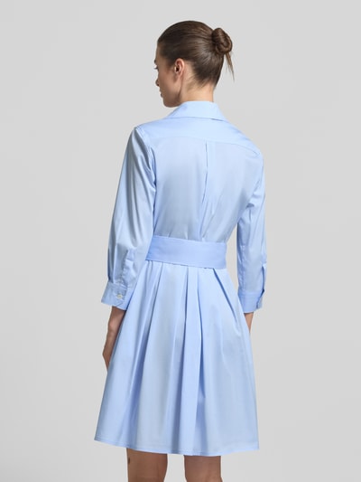 Modelka kobieca nosi Hemdblusenkleid mit Bindegürtel Modell 'JULE' od 0039 Italy, jasnoniebieska bawełna z domieszką stretchu, A-linia, długość do kolan, pasek, widok całej sylwetki z tyłu.