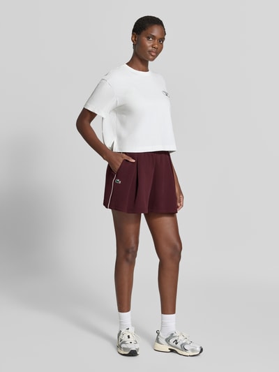 Vrouwenmodel draagt Relaxed Fit Shorts uit katoenmix van Lacoste, Dames sweatshorts, donkerrood en wit, Ganzkörperaanzicht van voren.