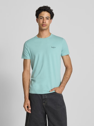 Mężczyznamodel nosi Slim Fit T-Shirt aus Baumwoll-Mix Modell 'ORIGINAL BASIC 3N' von Pepe Jeans w kolorze jasnoniebieskim, jednobarwny, z nadrukiem logo, okrągły dekolt, krótki rękaw, materiał jersey; krój slim fit; widok całej sylwetki z przodu.
