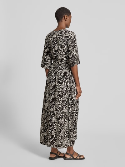 Frauenmodel trägt B.Young Midikleid aus reiner Viskose mit Tunikakragen, taillierter Schnitt, Bindegürtel, 3/4-Arm, schwarz-weiß gemustert, Ganzkörperansicht Rückansicht.