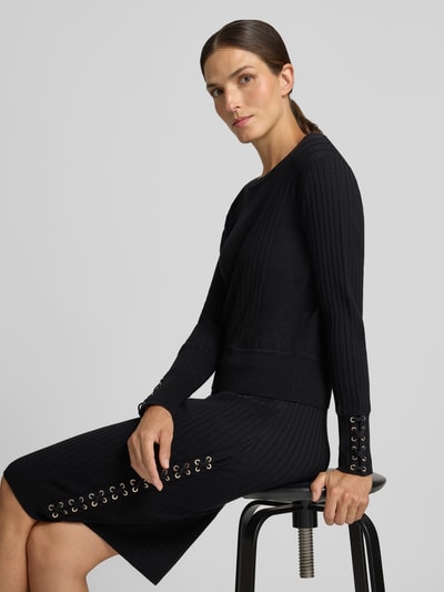 Vrouwenmodel draagt gebreide pullover uit viscosemix Model 'MAGLIA' van Liu Jo, Smal pasvorm, ribboorden, ruglengte maat S 54 cm, mouwlengte maat S 61 cm, kleur zwart, rechte lijnen structuur, detailopname zijkant