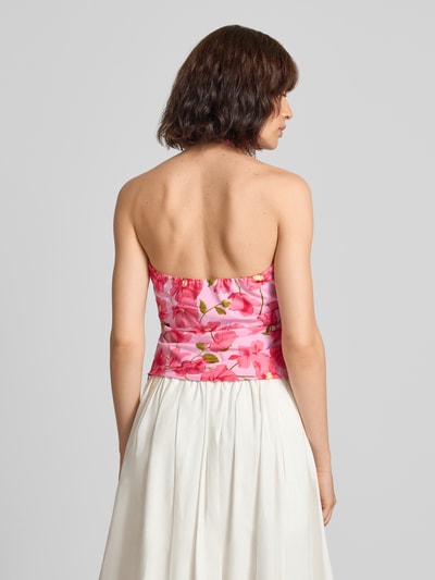 Frauenmodel trägt Blusentop im Allover-Look Modell 'CASTLE' von MANGO aus reiner Baumwolle, Slim Fit, Neckholder, rosa Muster, Ganzkörperansicht Rückansicht.