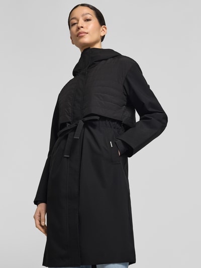 Frauenmodel trägt Mantel mit Kapuze und Tunnelzug Modell 'ELSA' von khujo, Damen Regular-Fit, schwarze Farbe, Ganzkörperansicht von vorne. Rückenlänge bei Größe S: 96 cm, Schulterbreite 49 cm, Brustweite 51 cm, Ärmellänge 60 cm.