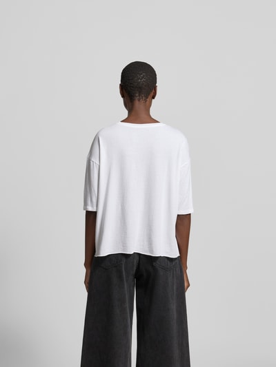 Frauenmodel trägt Relaxed Fit T-Shirt mit Modal-Anteil von Juvia in Weiß, Baumwoll-Modal-Mix, Halbarm, Rückenlänge 52 cm, Ganzkörperansicht Rückansicht.