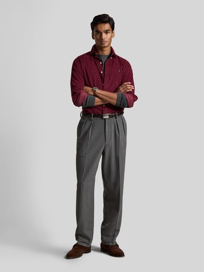 Männermodel trägt Custom Fit Freizeithemd aus reiner Baumwolle von Polo Ralph Lauren in Dunkelrot vor hellgrauem Hintergrund, Ganzkörperansicht von vorne.