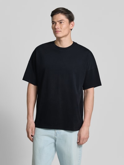 Männermodel trägt T-Shirt mit Rundhalsausschnitt Modell 'FIZVALLEY' von American Vintage in Schwarz, lockere Passform, Ganzkörperansicht von vorne.