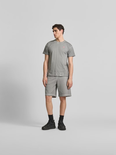 Männermodel trägt Regular Fit T-Shirt aus reiner Baumwolle von Diesel in Grau mit Rundhalsausschnitt, Used-Look, Label-Details, Rückenlänge 70 cm, Ganzkörperansicht von vorne.