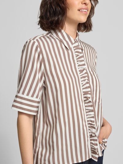 Kobieta nosi Regular Fit Hemdbluse aus Viskose-Mix Model 'VICA FRIL' od Brax, dwukolorowy wzór w paski, materiał splot twill, mieszanka wiskozy, krótki rękaw, detal: Brustasza, Kołnierzyk koszulowy, zapięcie na guziki, Ganzkörperansicht z przodu.
