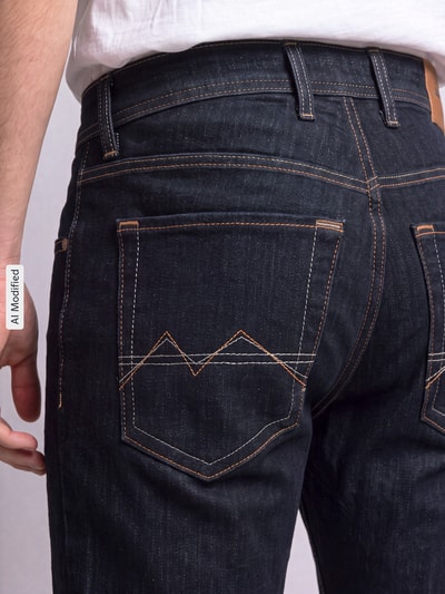 Männermodel trägt Straight Fit Jeans aus Baumwoll-Mix Modell 'Arne' von MAC in Dunkelblau mit Kontrastnähten, Nahaufnahme Rückansicht, Herren Straight Fit Jeans von MAC, KI-modifiziertes Bild.