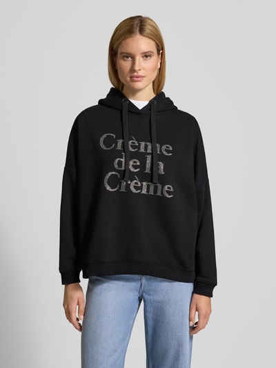 Frauenmodel trägt Oversized Hoodie mit Kapuze von miss goodlife in Schwarz, reine Baumwolle, Label-Detail vorn, Ganzkörperansicht von vorne.