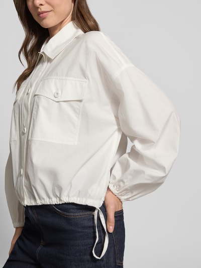 Frauenmodel trägt Loose Fit Blouson aus reiner Baumwolle Modell 'ORIGANO' von Weekend Max Mara in Optik: Unifarben mit Umlegekragen, Knopfleiste, Label-Applikation, Langarm, Brusttaschen, Material: reine Baumwolle, Struktur matt und glatt, Farbton Weiß, Nahaufnahme Oberkörper.