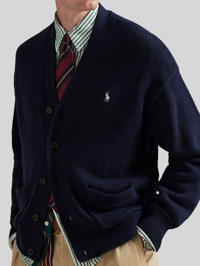 Męski model nosi Regular Fit Strickjacke aus reiner Baumwolle od Polo Ralph Lauren, granatowa, dzianinowa, z logo, guziki, kieszenie, krój regular fit, bawełna. Ujęcie: zbliżenie górnej części ciała.