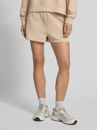 Kobiece model prezentuje Regular Fit Sweatshorts aus Baumwoll-Mix od Lacoste, efekt: jednolity kolor, krój regular fit, wyhaftowane logo, tunel, ściągacz, wpuszczane kieszenie, kieszeń z tyłu, dzianina dresowa, mieszanka bawełny, całkowite ujęcie z przodu.