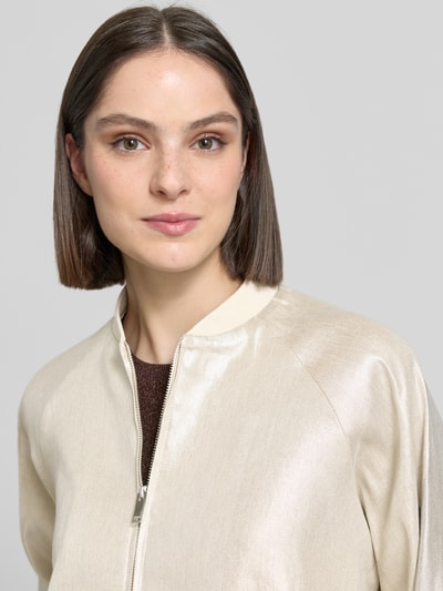 Frauenmodel trägt schimmernde Jacke mit Reißverschluss Modell 'Noema' von Someday, Stehkragen, Regular-Fit, Nahaufnahme Oberkörper. Rückenlänge bei Größe 36: 48 cm, Schulterbreite: 43 cm, Brustweite: 64 cm, Ärmellänge: 46 cm.