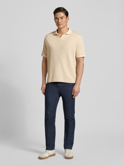 Männermodel trägt Regular Fit Poloshirt mit V-Ausschnitt Modell 'ACAYO' von Drykorn in Beige, Baumwoll-Mix, Ganzkörperansicht von vorne.
