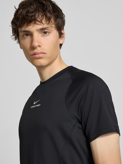 Männermodel trägt T-Shirt mit Logo-Print und Raglanärmeln von NIKE TRAINING, Schwarz, Rundhalsausschnitt, Nahaufnahme Oberkörper.