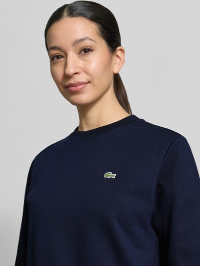 Frauenmodel trägt Relaxed Fit Sweatshirt aus reiner Baumwolle von Lacoste Sport, Optik: Unifarben, Logo-Stitching, Nahaufnahme Oberkörper.