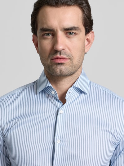 Männermodel trägt Slim Fit Businesshemd aus reiner Baumwolle Modell 'HANK' von BOSS, gestreift mit Haifischkragen, Nahaufnahme Oberkörper.