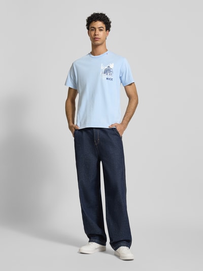 Männermodel trägt Regular Fit T-Shirt mit Logo-Print von Replay aus reiner Baumwolle, Rundhalsauschnitt, Statement-Print, Ganzkörperansicht von vorne.