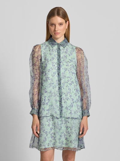 Kobiece modelka nosi Knielanges Kleid aus Seide mit Knopfleiste von Marc Cain, wzór na całej powierzchni, półprzezroczysty jedwab, prosty krój, długość do kolan, kołnierzyk koszulowy, listwa guzikowa, długość tyłu w rozmiarze 36: 94 cm, szerokość w rozmiarze 36: 50 cm, długość rękawów w rozmiarze 36: 64 cm. Ganzkörperansicht von vorne.