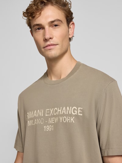 Männermodel trägt Relaxed Fit T-Shirt aus reiner Baumwolle mit Logo-Print von Armani Exchange in Beige mit Rundhalsausschnitt, Nahaufnahme Oberkörper.