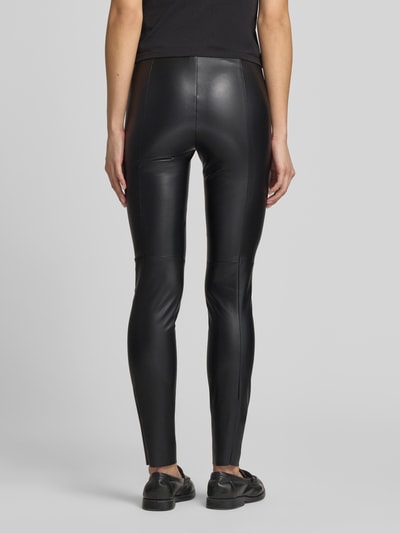 Frauenmodel trägt Leggings in Leder-Optik von Marc Cain, Figurbetont, Elastischer-Bund, Teilungsnähte, Ganzkörperansicht Rückansicht.