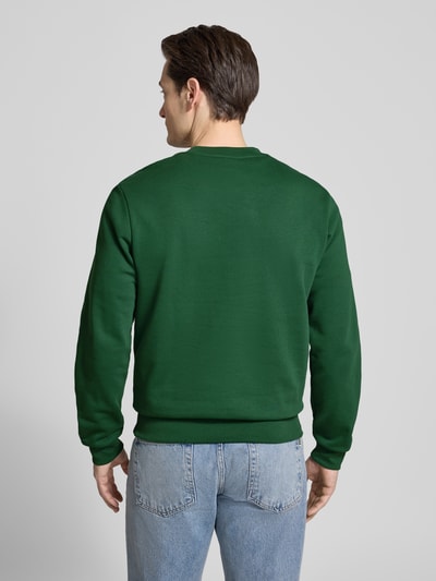 Männermodel trägt Regular Fit Sweatshirt aus katoenmix van Lacoste, look: effen, labelpatch, ronde hals, lange mouw, rompzoom geribd, geheel in donkergroen, ganzkörperansicht rückansicht