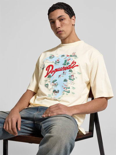 Männermodel trägt Loose Fit T-Shirt mit Logo-Print von Dsquared2, cremefarben mit buntem Aufdruck, reine Baumwolle, Nahaufnahme Oberkörper.