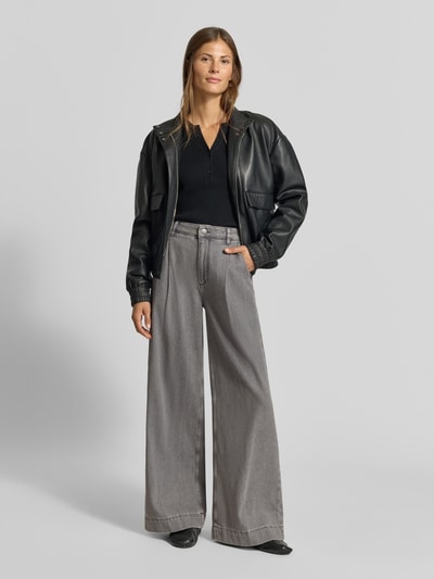 Frauenmodel trägt Wide Fit Jeans mit gelegten Falten von MYON aus reiner Baumwolle, graue Farbe, Seiten- und Gesäßtaschen, Ganzkörperansicht von vorne.