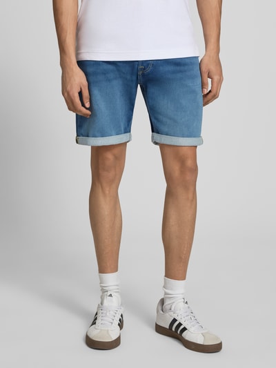 Mężczyzna nosi Regular Fit Jeansshorts mit Umschlag Modell 'RICK' od Jack & Jones, bawełna z domieszką wiskozy, używany wygląd, szerokość w rozmiarze M: 42 cm, długość nogawki wewnętrznej: 20 cm, zdjęcie z przodu, zbliżenie na dolną część ciała.