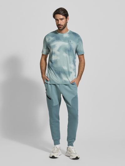 Męski model nosi Sweatpants mit Logo Modell 'Unstoppable' od Under Armour w regularnym kroju, kolor niebieski, elastyczny pas, logo, spodnie z bawełnianą domieszką, długość nogawki 72 cm, pełen widok sylwetki z przodu.