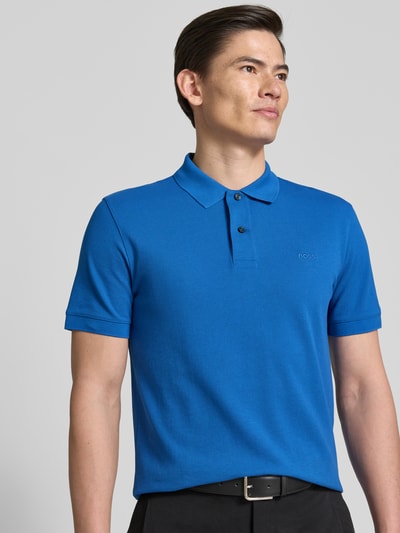 Männermodel trägt Regular Fit Poloshirt aus reiner Baumwolle Modell 'PALLAS' von BOSS, unifarbenes Blau, Piqué-Struktur, Nahaufnahme Oberkörper.