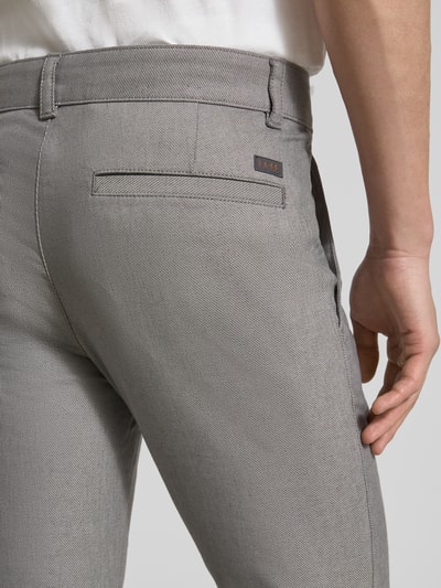 Mężczyzna nosi Slim Fit Chino aus Baumwoll-Mix mit Leinen und Viskose-Anteil Modell 'Chino-Slim-2' od BOSS Orange, optyka denim, detal kieszeni i label patch, przetkanie twill, kolor szary, nahaufnahme tył.